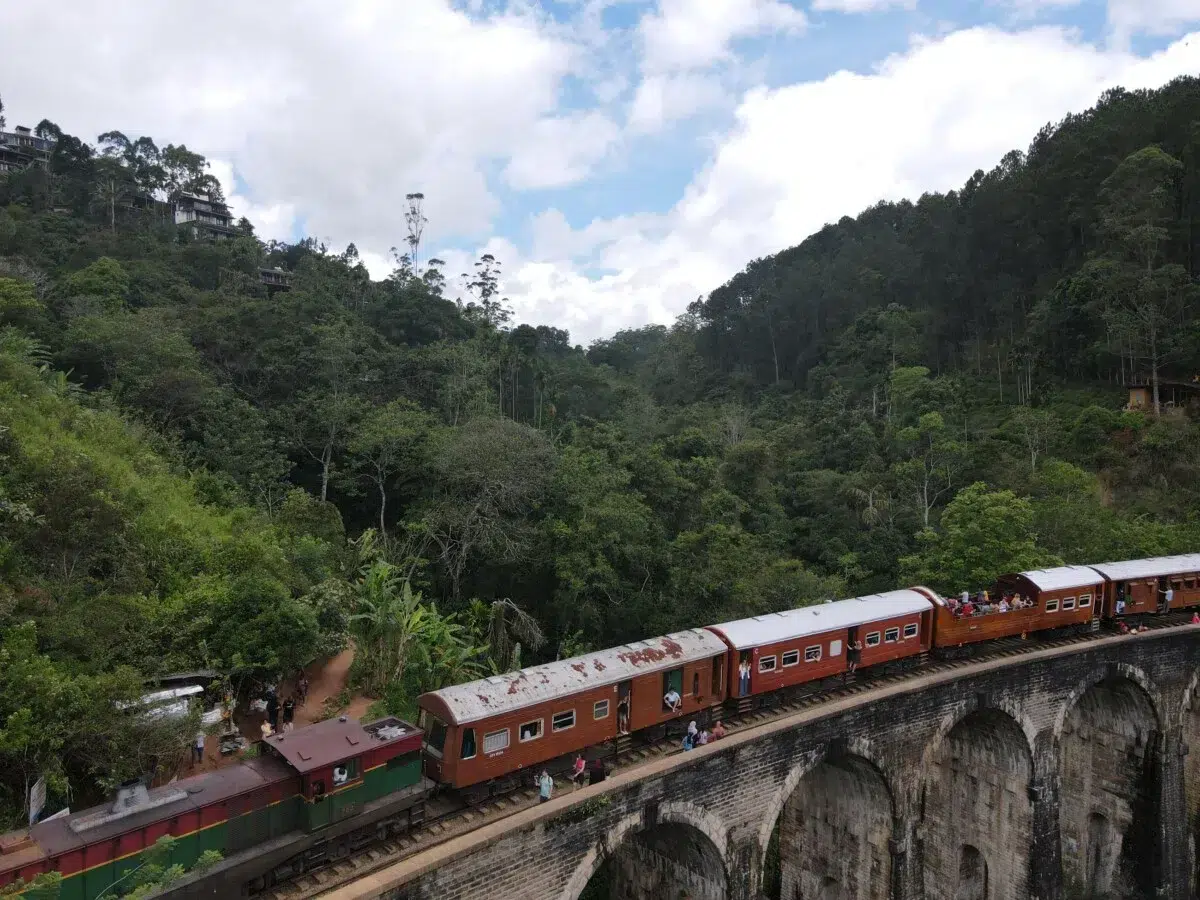 A train crossing the Nine Arches Bridge near Ella, surrounded by forest
