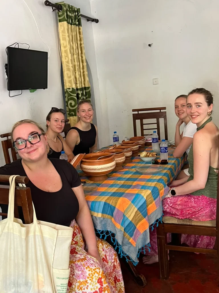 Five travellers seated at a village dining table before a Sri Lankan home cooked meal