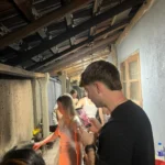 Guests gathered in a traditional Sri Lankan kitchen with wooden rafters during a village cooking class