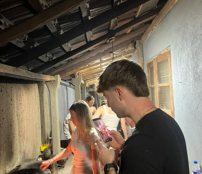 Guests gathered in a traditional Sri Lankan kitchen with wooden rafters during a village cooking class