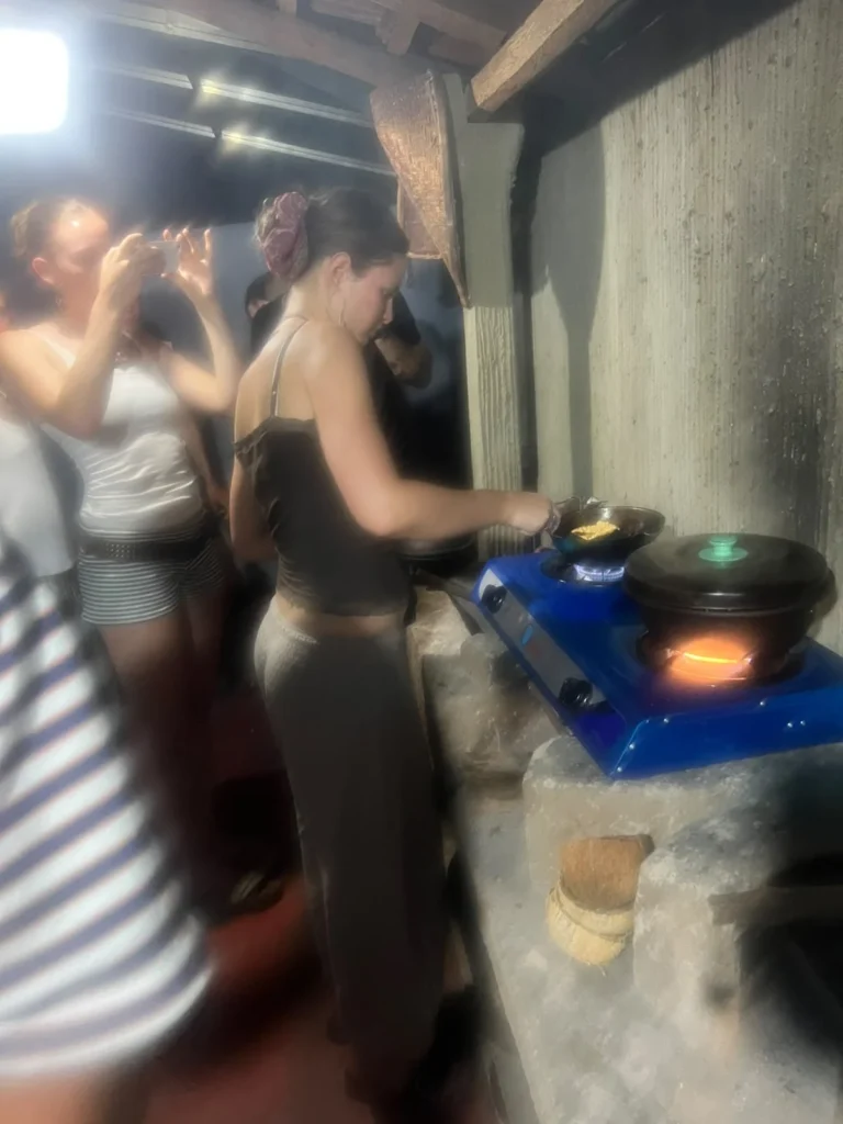 Traveller cooking over a stone hearth at a Sri Lankan village cooking class, clay pot heating over the fire