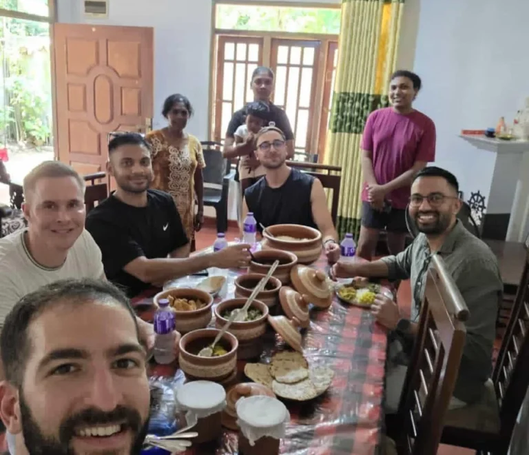 Cooking class guests and the host family seated around a table of Sri Lankan curries in clay pots