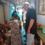 Sri Lankan host cooking over an open wood fire while cooking class guests watch