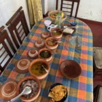 Sri Lankan rice and curry spread in clay pots on a village dining table, with red rice, dhal, green bean curry and papadam