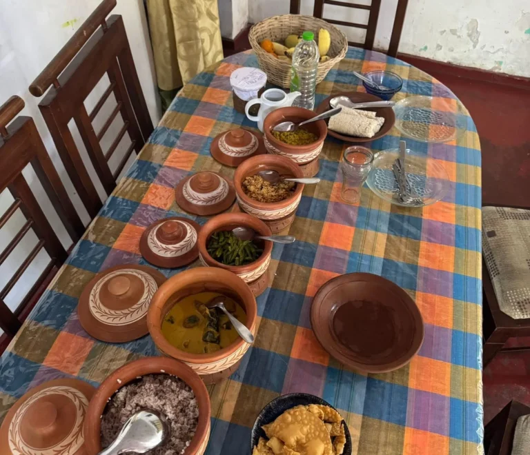 Sri Lankan rice and curry spread in clay pots on a village dining table, with red rice, dhal, green bean curry and papadam